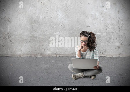 Young Girl using laptop in empty room Banque D'Images