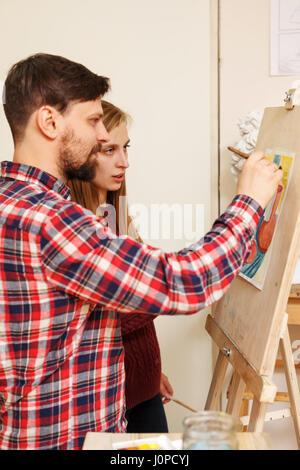 L'enseignant explique les règles du dessin à l'aquarelle à l'étudiant. L'école de dessin pour les adultes. Les cours de maîtrise. Banque D'Images