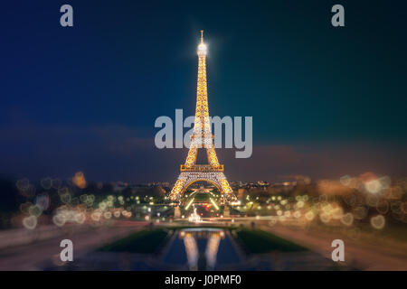 La Tour Eiffel vu de Jardins du Trocadéro. La Tour Eiffel illuminée se reflète sur l'eau du Tracadero fontaines dans la soirée. Bokeh en forme de h Banque D'Images