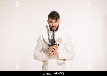 Studio shot of a happy young chef barbu tenant des couteaux sur fond blanc. Chef avec couteau. Beau graves en colère cheef détenant plusieurs sharp Banque D'Images