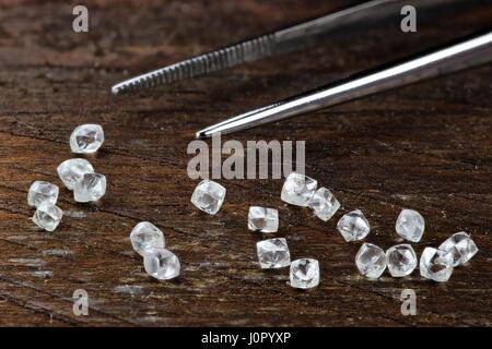 Les diamants bruts avec des pincettes sur fond de bois Banque D'Images