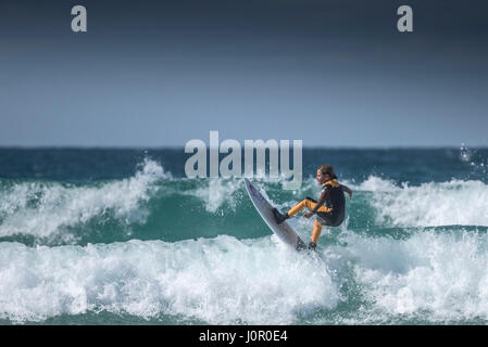 UK Surf ; un jeune surfer une vague. Enfant surf wave. Banque D'Images