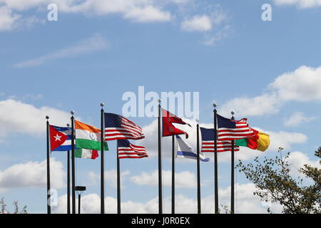 Les drapeaux US, au Népal, au Cameroun, Israël, l'Inde, le Mexique et Cuba sur un mât dans le vent contre un ciel bleu et nuages blancs. Le vent souffle. Banque D'Images