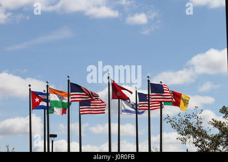 Les drapeaux US, au Népal, au Cameroun, Israël, l'Inde, le Mexique et Cuba sur un mât dans le vent contre un ciel bleu et nuages blancs. Le vent souffle. Banque D'Images