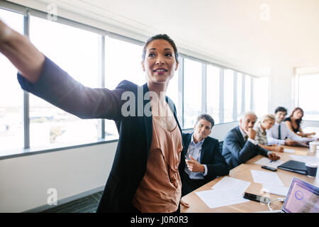 Présentation dans la salle de conférence moderne avec asian businesswoman montrant quelque chose d'important à mes collègues assis en arrière. Mature asian woman presenting Banque D'Images