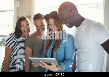 Jeune femme tenant et montrant le comprimé dans groupe de trois amis que sourire et avoir du plaisir. Banque D'Images