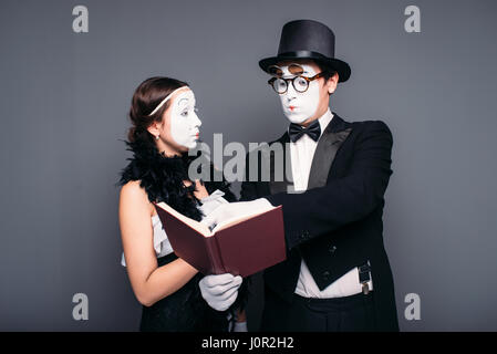 Deux artistes de théâtre pantomime posant avec un livre. Mime acteur et actrice effectuant Banque D'Images