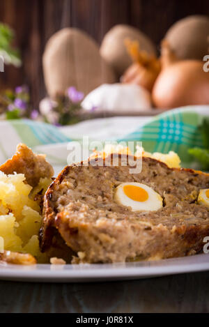 Photo verticale avec deux tranches de pain de Pâques faits maison qui est rempli par des oeufs de cailles et est servi avec pommes de terre oignon maillé sur plaque blanche. Subst Banque D'Images