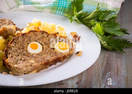 Photo horizontale avec deux tranches de pain de Pâques faits maison qui est rempli par des oeufs de cailles et est servi avec pommes de terre oignon maillé sur plaque blanche. Dans Banque D'Images