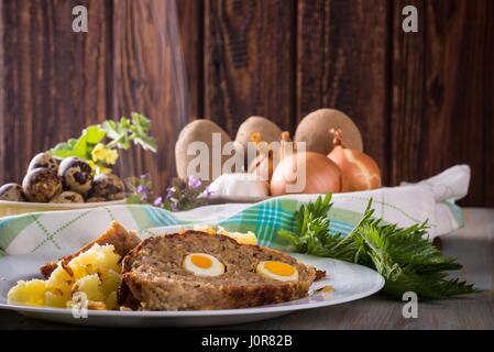 Photo horizontale avec deux tranches de pain de Pâques faits maison qui est rempli par des oeufs de cailles et est servi avec pommes de terre oignon maillé sur plaque blanche. Dans Banque D'Images