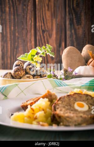 Photo verticale de bol jaune pleine d'oeufs de cailles à côté de partie de pain de Pâques rempli par des œufs avec des pommes de terre et de maillage avec des légumes. Peu de fl Banque D'Images