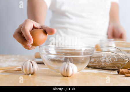 Close up shot part of woman holding egg pour freinage shell avec bol en verre à faire bakery Banque D'Images