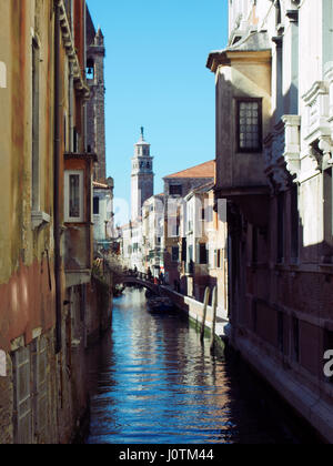 De vieux bâtiments de Venise à côté d'un petit canal avec un pont se reflétant dans l'eau des bateaux et un ciel bleu Banque D'Images