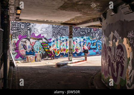 La patineuse adolescent équitation une planche à roulettes d'effectuer un ollie dans Leake Street tunnel, Londres, Royaume-Uni. Leake street aussi connu sous le nom de "Tunnel Graffiti' ou 'Banques Banque D'Images