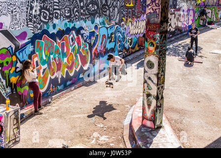 La patineuse adolescent équitation une planche à roulettes d'effectuer un ollie dans Leake Street tunnel, Londres, Royaume-Uni. Leake street aussi connu sous le nom de "Tunnel Graffiti' ou 'Banques Banque D'Images