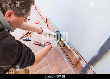 Un jardinier sont définition d'une minuterie d'arrosage électronique sur une terrasse. Luxueux et coûteux système d'irrigation goutte à goutte en cuivre pour les plantes en pots et fleurs Banque D'Images