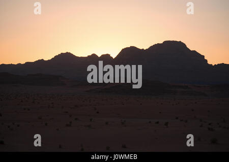 Un coucher de soleil sur les grandes lignes d'une montagne sombre dans le désert de Wadi Rum, la célèbre vallée de la lune à la recherche comme la planète de Mars Banque D'Images