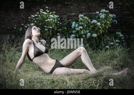 Young woman in bikini laying in garden Banque D'Images