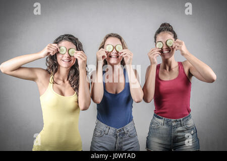 3 women holding concombre à leurs yeux Banque D'Images