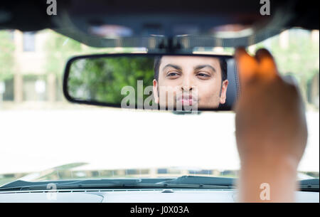 Closeup portrait, beau jeune homme égoïste en bleu polo shirt à miroir au reflet montrant des baisers et duck face, admirant son apparence Banque D'Images