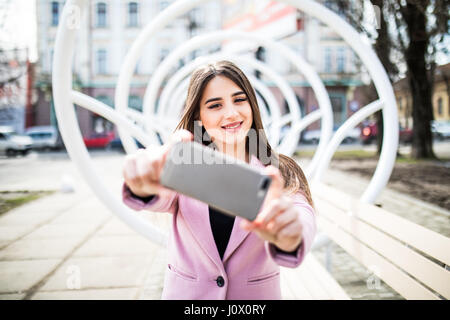 Libre-selfies portrait joli fille sur la rue en ville. Elle a les lèvres vinique, souriant à l'appareil photo Banque D'Images