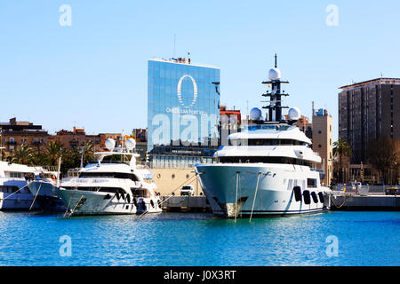 Vedette à moteur yachts de luxe et amarré dans le Port Vell, Barcelone, Catalogne, Espagne. Dans l'arrière-plan est le 'One Ocean Port Vell' immeuble à appartements. Banque D'Images