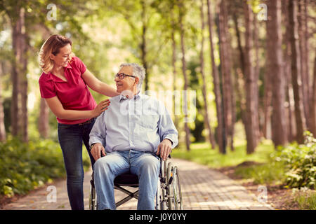 Femme souriante avec son père en fauteuil roulant piscine handicapés Banque D'Images