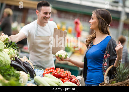 Woman smiling and holding le chou-fleur à la rue du marché Banque D'Images