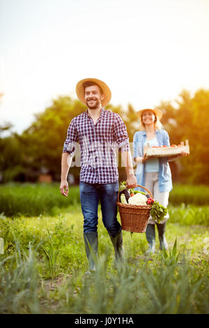 Les agriculteurs satisfaits qui reviennent d'un couple avec des légumes du jardin Banque D'Images