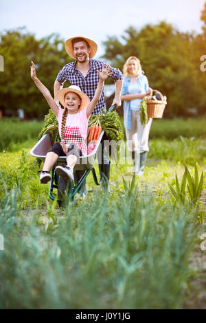 Happy girl retour de jardin avec brouette en père Banque D'Images