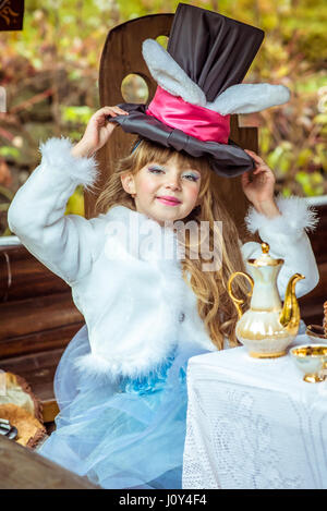 Un peu de belle fille holding hat cylindre avec les oreilles comme un lapin sur la tête à la table Banque D'Images