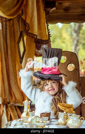 Un peu de belle fille holding hat cylindre avec les oreilles comme un lapin sur la tête à la table Banque D'Images