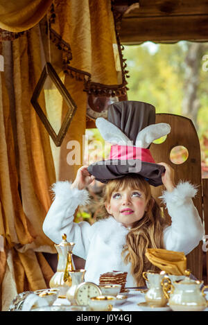 Un peu de belle fille holding hat cylindre avec les oreilles comme un lapin sur la tête à la table Banque D'Images