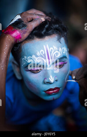 Jeune homme ayant son visage peint à l'Bédeille et charak festival en Krishnadepur, West Bengal Banque D'Images