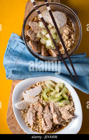 Deux bols de soupe aux nouilles ramen, le céleri, le poulet et le bleu verticale serviette Banque D'Images