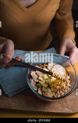 Woman eating soupe avec nouilles ramen au poulet et le céleri à la verticale Banque D'Images
