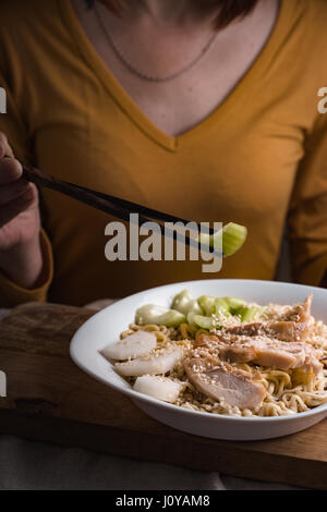 Femme mangeant des bâtonnets de céleri et verticale des nouilles ramen Banque D'Images
