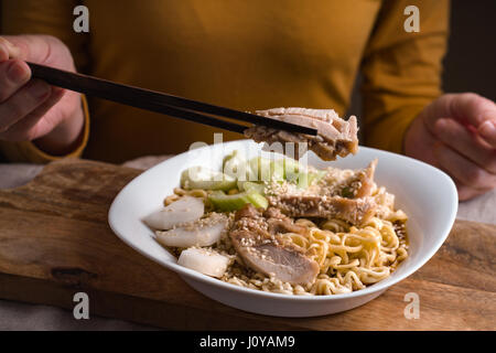 Woman eating baguettes poulet et nouilles ramen l'horizontale Banque D'Images