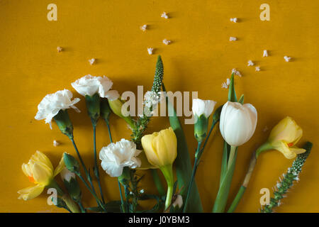 Tulipes et œillets sur une table jaune Banque D'Images