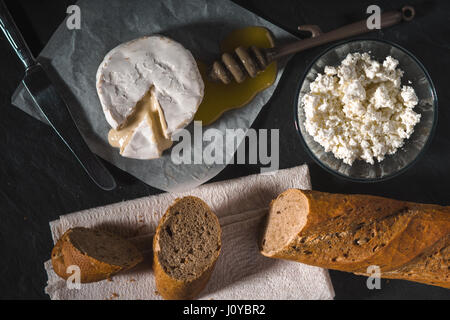 Fromage Brie, le fromage cottage, le miel sur parchemin Banque D'Images