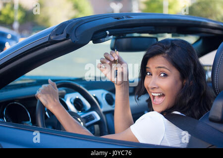 Closeup portrait, jeune gai, joyeux, souriant, gorgeous woman holding up pour sa première voiture de sport. La satisfaction du client Banque D'Images