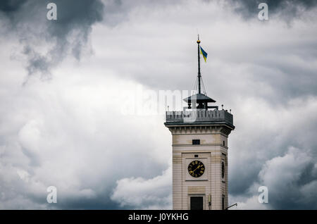 Tour de l'horloge de l'hôtel de ville de Lviv avec pavillon ukrainien en haut contre le ciel nuageux orageux, l'Ukraine. La notion de courage et de puissance ou nerveusement Banque D'Images