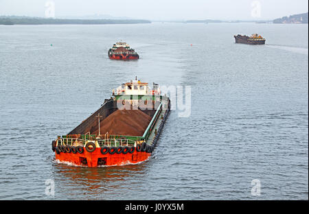 De grandes barges cargo transport de minerai de fer extrait en arrière-pays pour le port principal pour le chargement dans les gros navires pour l'exportation, le long de la rivière Mandovi à Goa. Banque D'Images