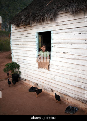 Jeune fille cubaine à la recherche par la fenêtre d'une maison en bois dans la région de Trinidad, Cuba Banque D'Images