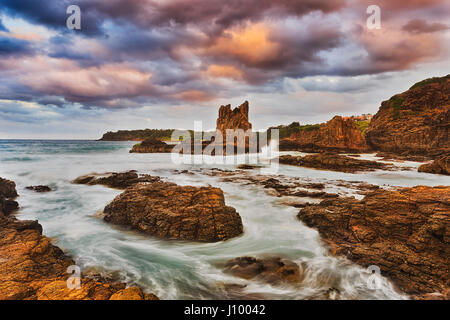 De soleil colorés à Bombo beach et cathédrale des rochers sur Kiama, côte du Pacifique de l'Australie. Des rochers de grès érodées illuminée par un coucher de soleil chaud. Banque D'Images