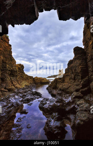 Grotte rocheuse isolée résultat de l'érosion de la mer à la Cathédrale de grès roches de Pacific Coast en Australie près de Kiama au coucher du soleil. Banque D'Images
