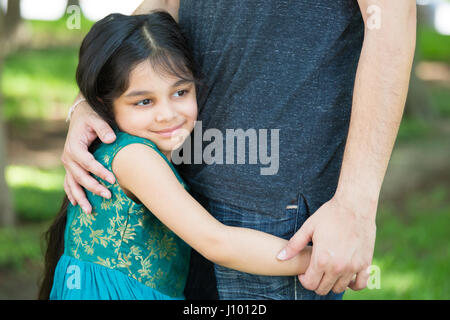 Closeup portrait, jeune enfant serrant tendrement son père, isolé à l'extérieur extérieur fond d'herbe verte. Daddy's little girl Banque D'Images