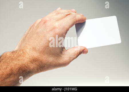 Main mâle détient plus de carte vide blanc fond gris, la photo en gros Banque D'Images