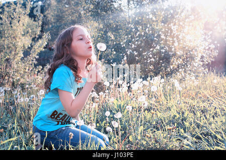 Teen girl blowing seeds à partir d'une fleur de pissenlit spring park Banque D'Images