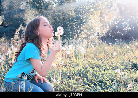 Teen girl blowing seeds à partir d'une fleur de pissenlit spring park Banque D'Images